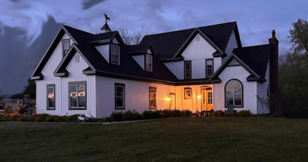 Modern farmhouse look featuring vertical board and batten siding, dark rooflines, and warm exterior lighting